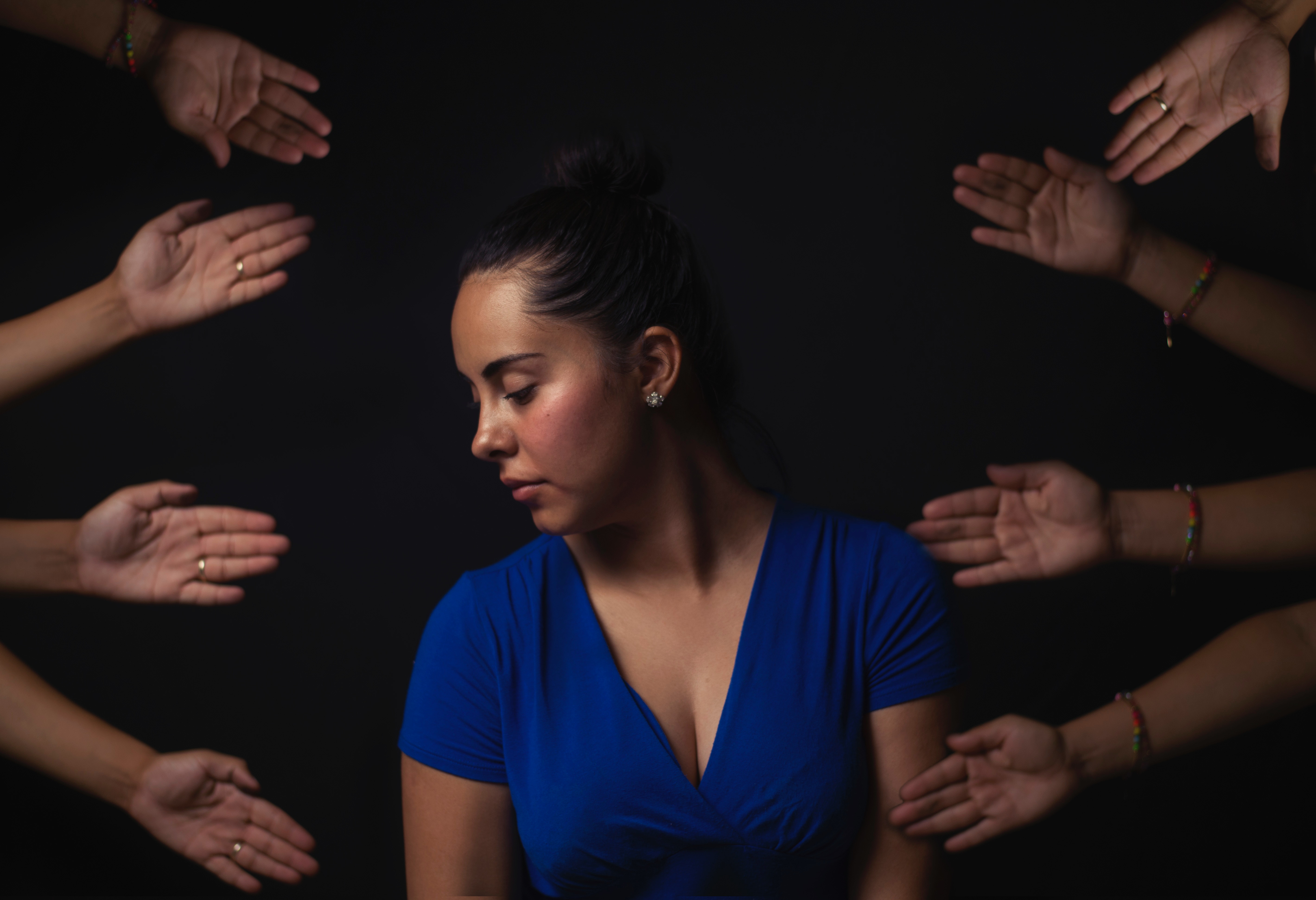 woman surrounded by other peoples open hands